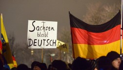 Teilnehmer der islamkritischen Pegida-Bewegung halten am 05.01.2015 Deutschland-Fahnen und ein Plakat mit der Aufschrift «Sachsen bleibt DEUTSCH» bei einer Kundgebung in Dresden (Sachsen). Foto: Peter Endig/dpa